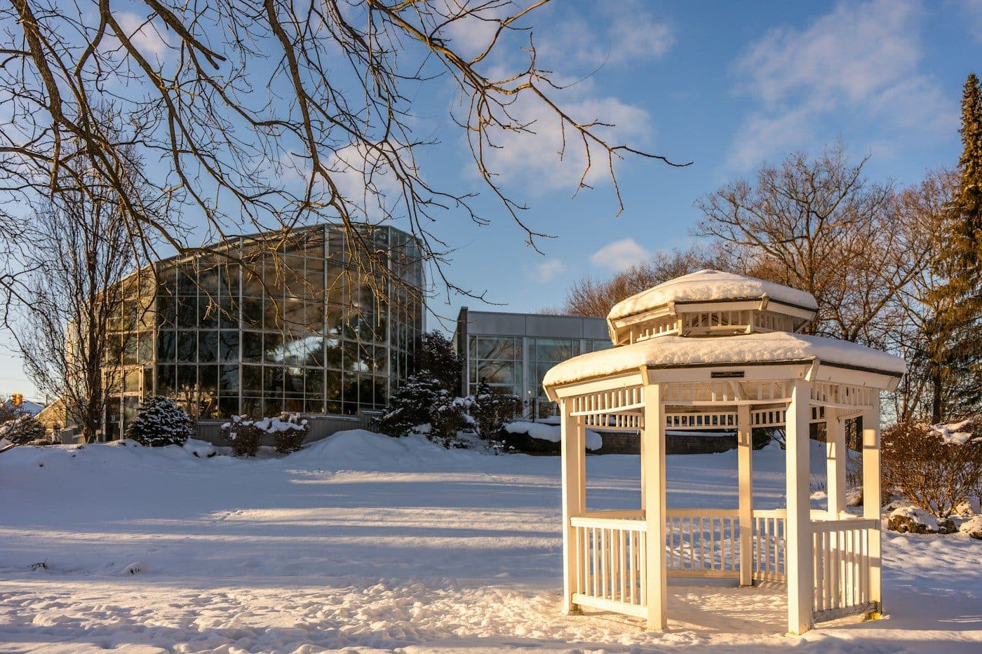 Verschneiter Garten mit Pavillon vor einem Glasgebäude