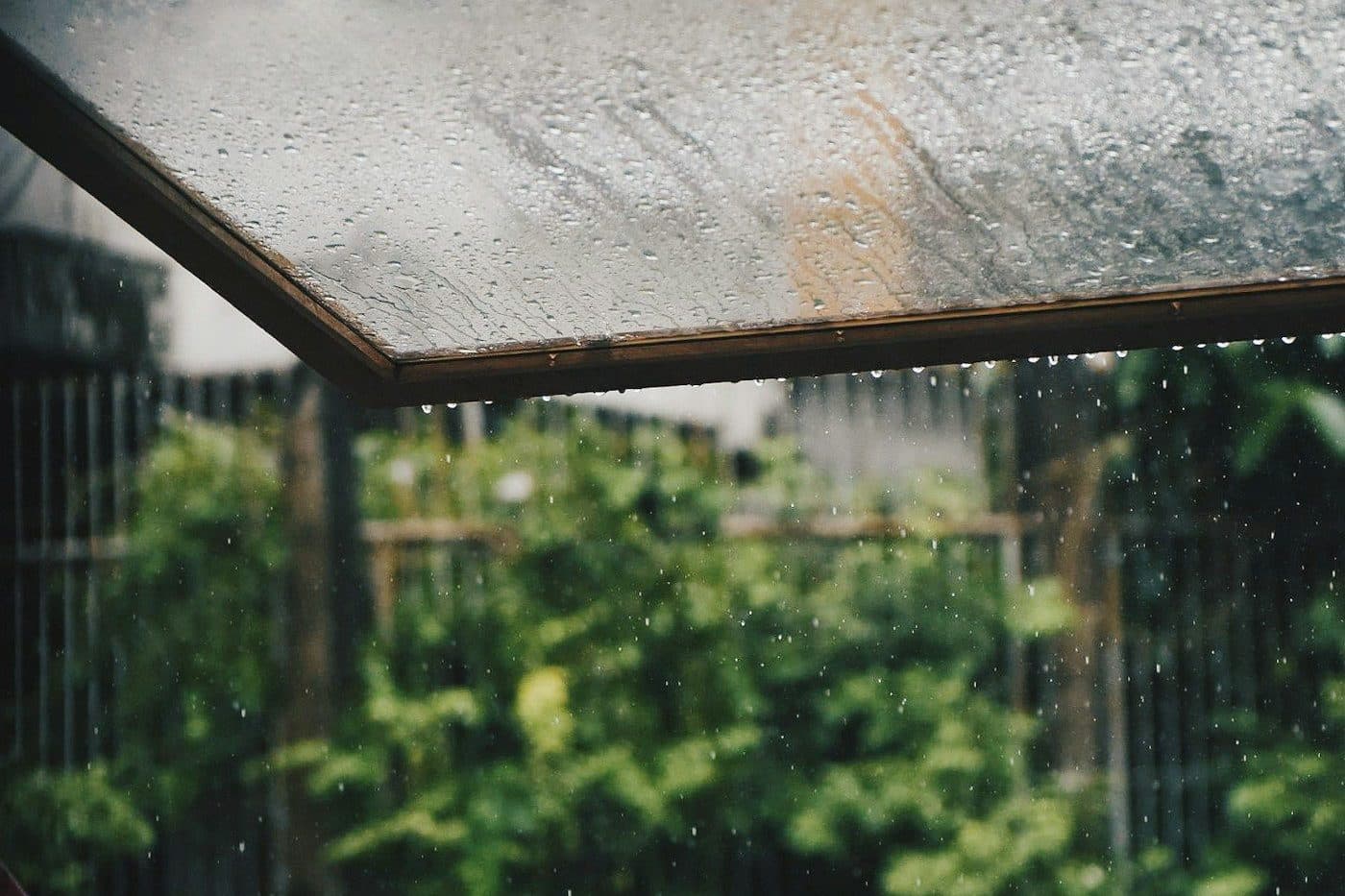Regentropfen auf einer Glasscheibe über einer Terrasse
