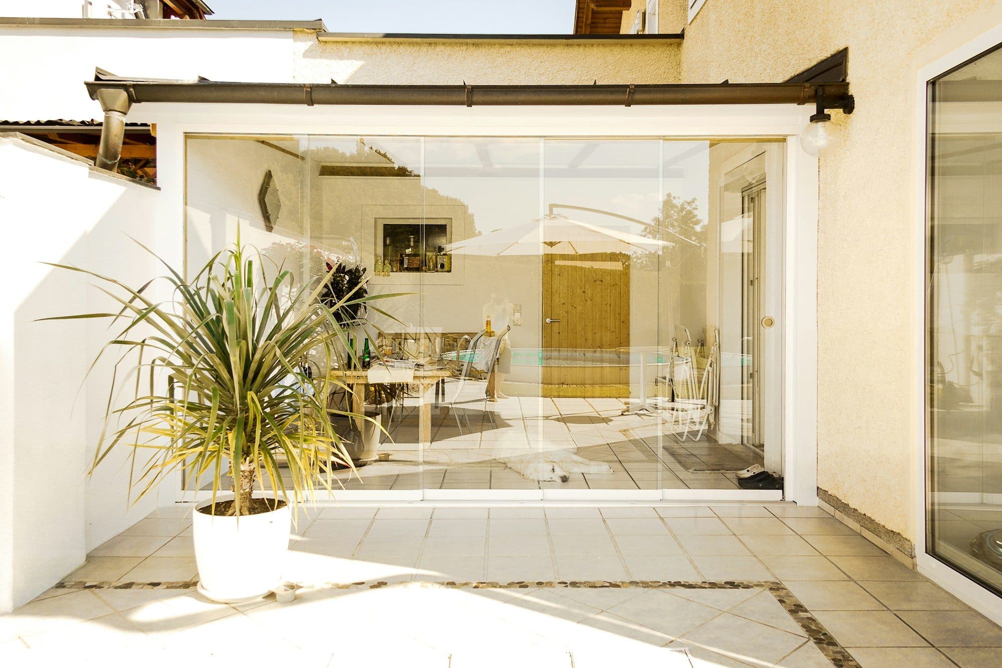 Überdachte Terrasse mit rahmenlosen Glasschiebewänden