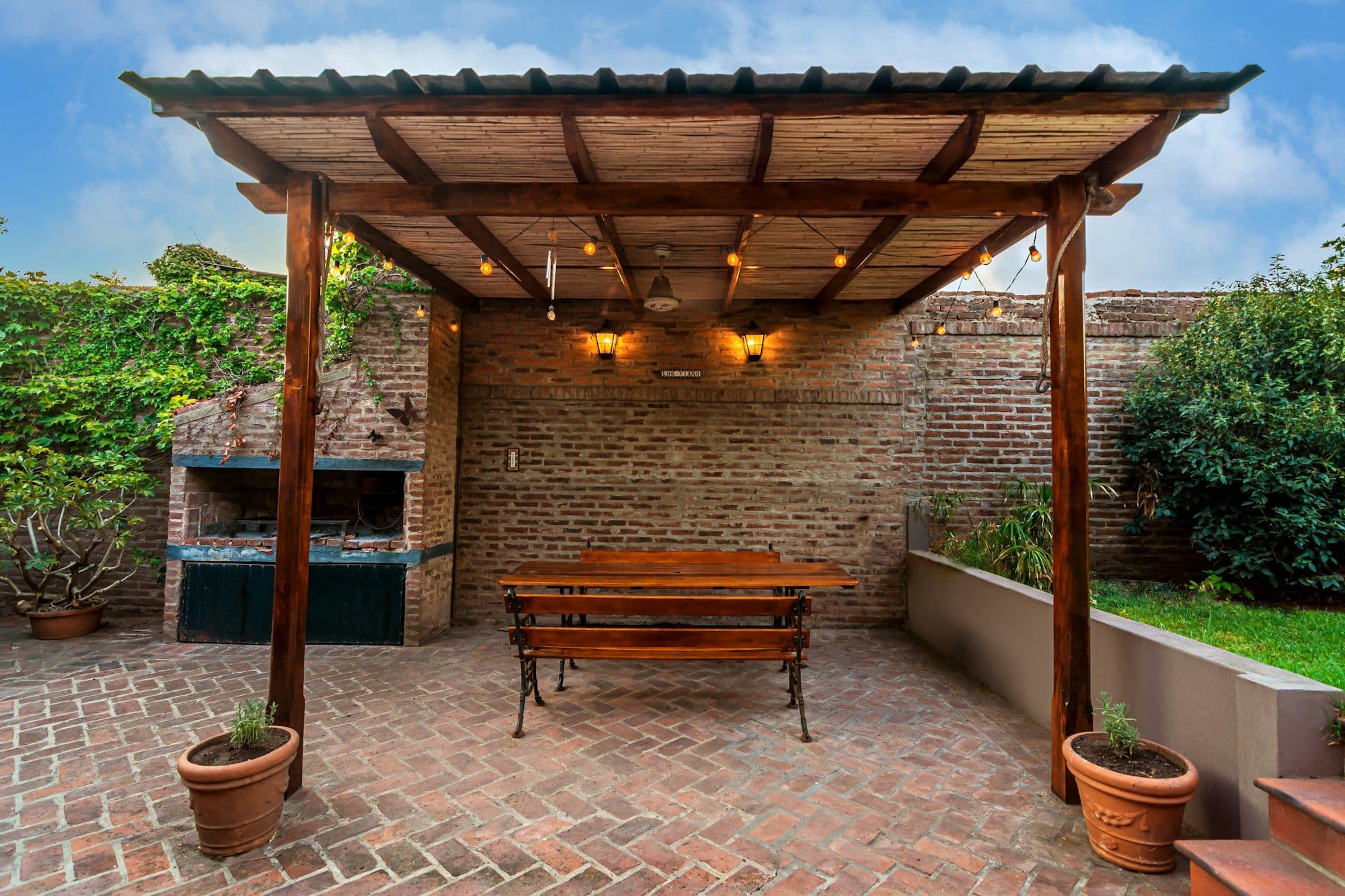 Terrassenüberdachung aus Holz über einer gepflasterten Terrasse mit Sitzbank
