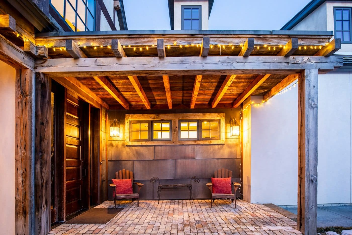 Überdachte Holzterrasse mit Balken und warmer Beleuchtung am Abend