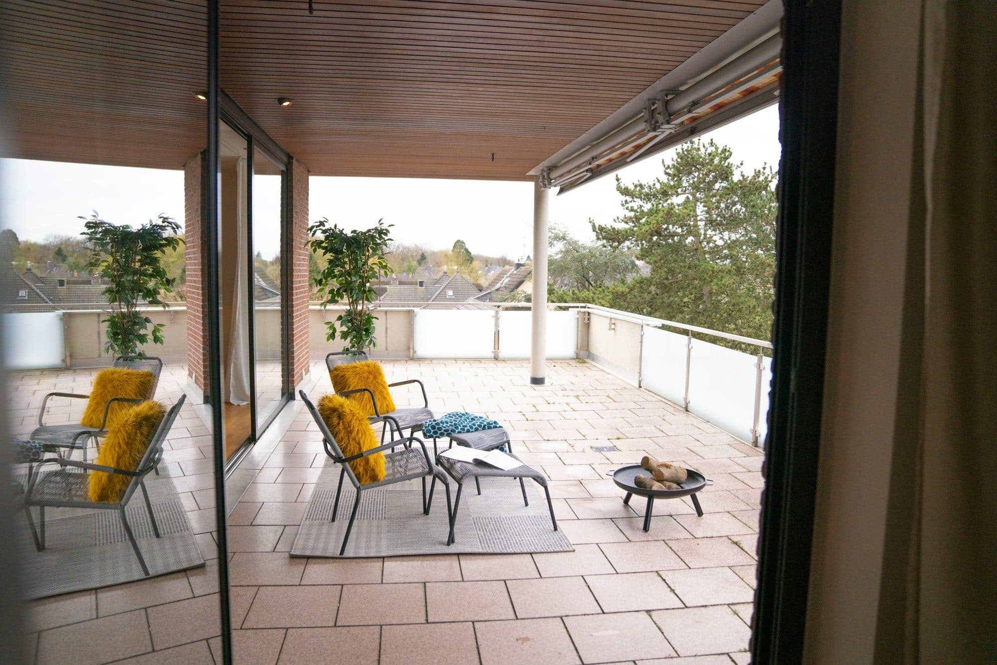 Überdachte Dachterrasse mit Sitzgruppe und Blick ins Grüne