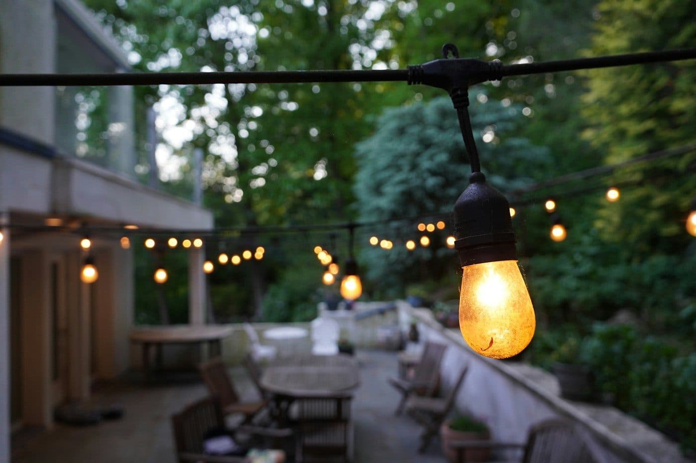 Warmweiße Glühbirne einer Lichterkette über einer Terrasse