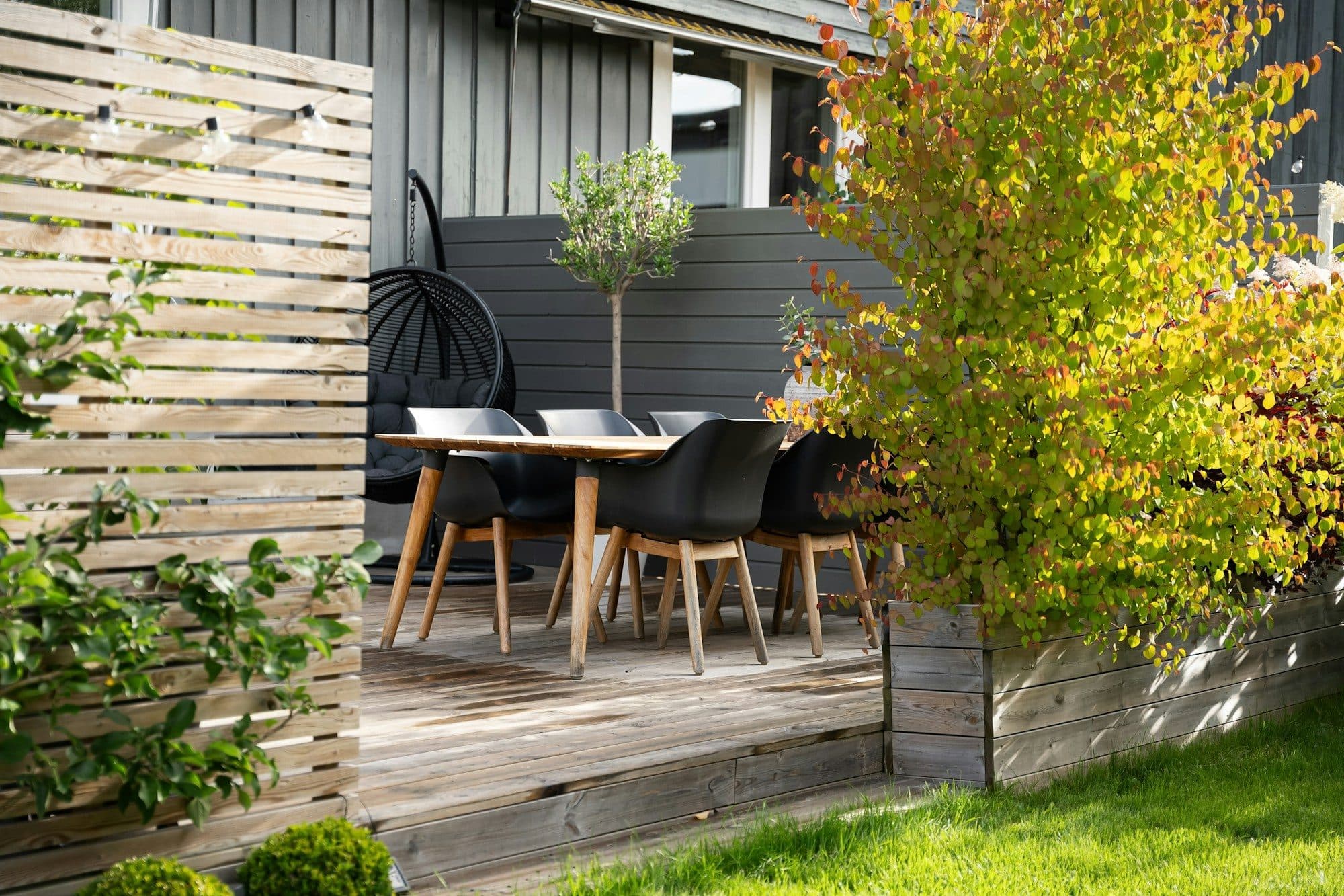 Terrasse mit Esstisch und Sichtschutzwand aus Holzlamellen