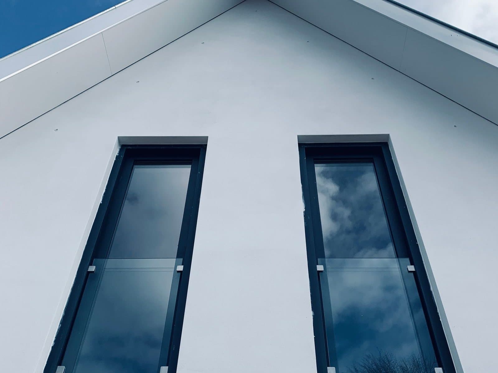 Zwei hohe Fenster mit anthrazitfarbenen Rahmen in einer hellen Fassade